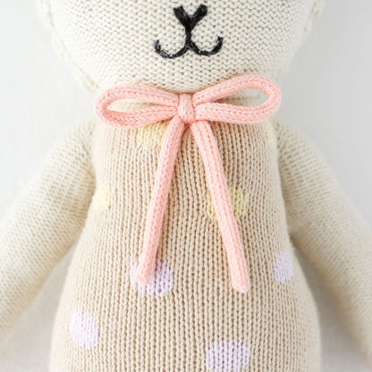 A close-up showing hand-knit details on Lucy the lamb, including her pink yarn bow.