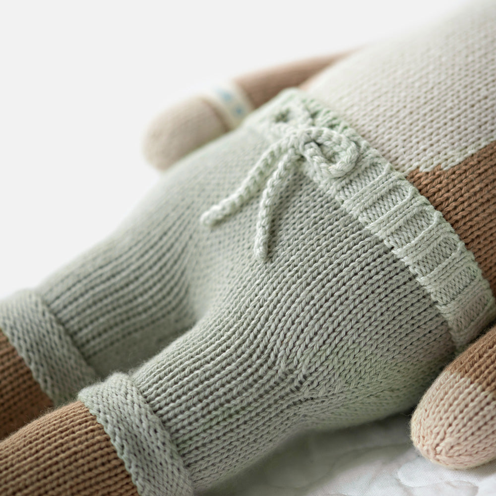 A close-up showing hand-knit details on Elliott the fawn, including a bow on his shorts.