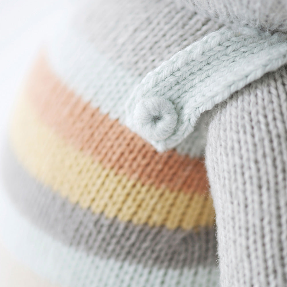 A close-up showing a knit button on the shoulder of Evan’s overalls.