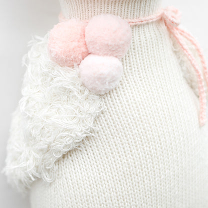 A close-up showing Harlow’s fluffy, hand-knitted wings and fluffy pink pom-poms on her neck.