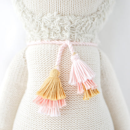 A close-up showing Lola the llama’s pink and yellow yarn tassels.