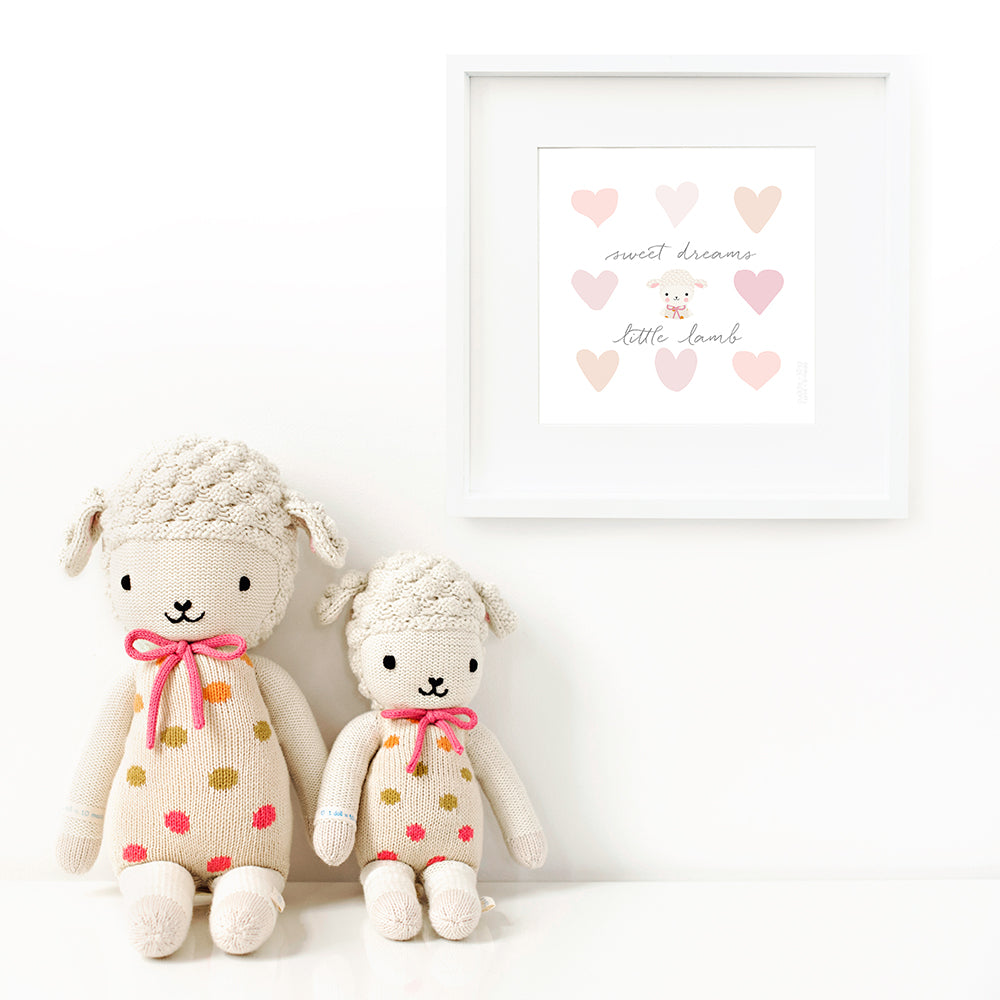 Two Lucy the lamb stuffed animals sitting beside a framed print with a picture of Lucy that says “Sweet dreams, little lamb.”