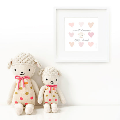 Two Lucy the lamb stuffed animals sitting beside a framed print with a picture of Lucy that says “Sweet dreams, little lamb.”