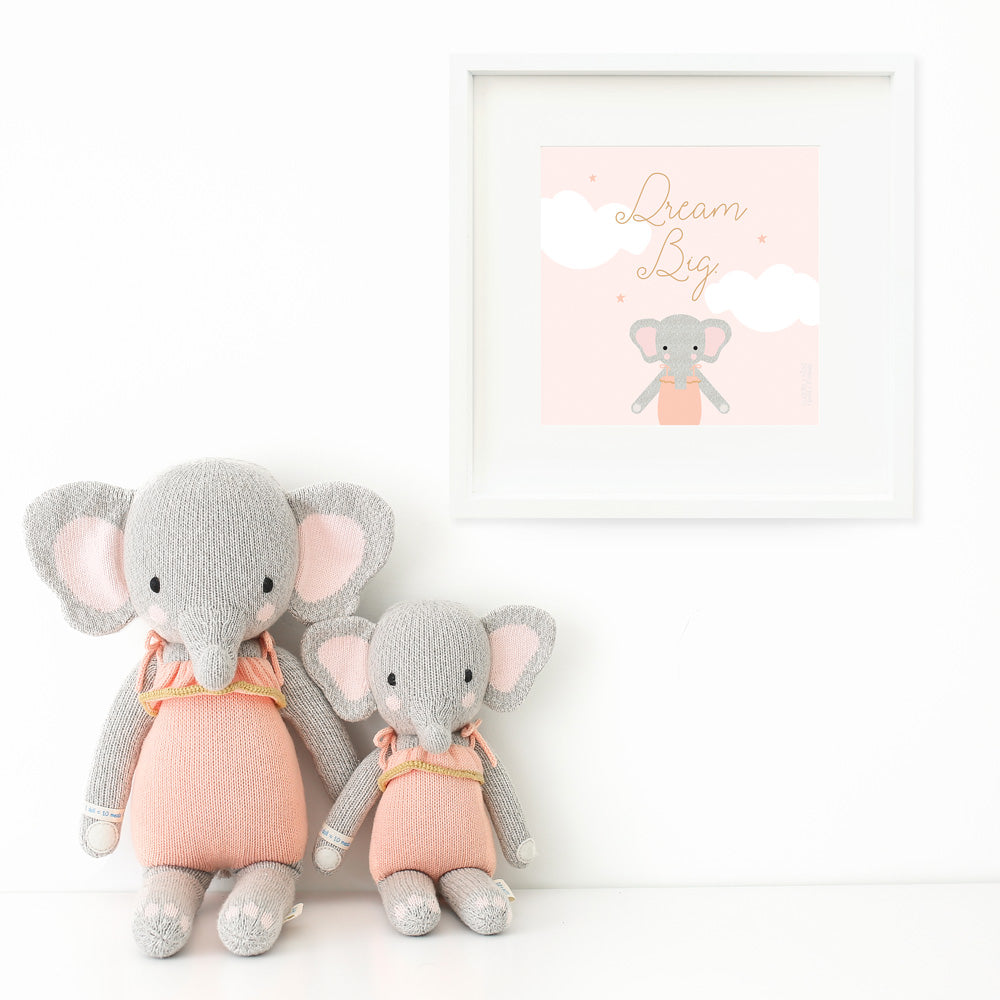 Two Eloise the elephant stuffed animals sitting beside a framed print with a picture of Eloise that says “Dream big.”