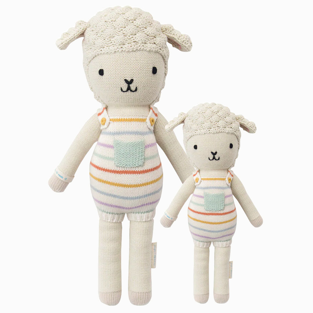 Avery the lamb in the regular and little sizes, shown from the front. Avery is wearing a pair of rainbow striped overalls with a light blue pocket on the front.