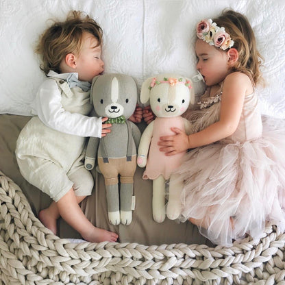 Two sleeping babies lying side-by-side with two knit stuffed animals, Noah the dog and Charlotte the dog.