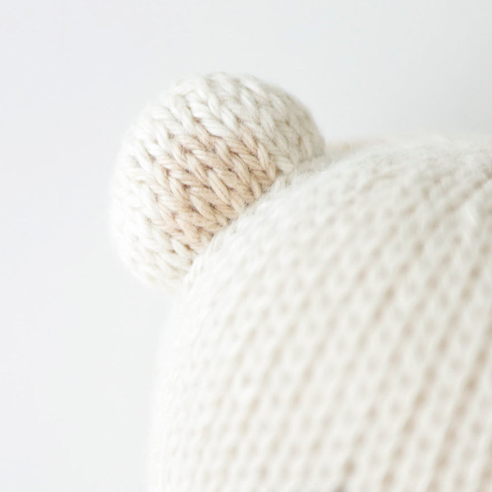 A close up showing the hand-knit details on baby polar bear's small, rounded ears.