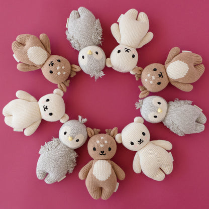 Three baby animal stuffed dolls standing in a row: baby fawn, baby penguin and baby polar bear.