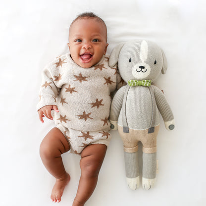 A laughing baby holding a Noah the dog stuffed doll.